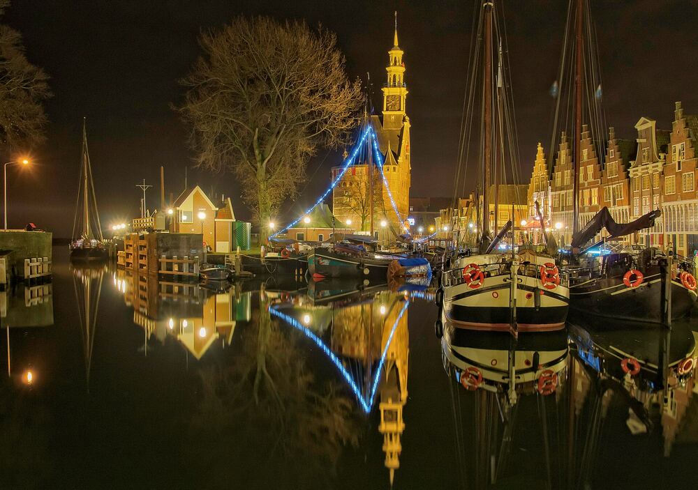 De Hoofdtoren aan de verlichte haven van Hoorn in de avond